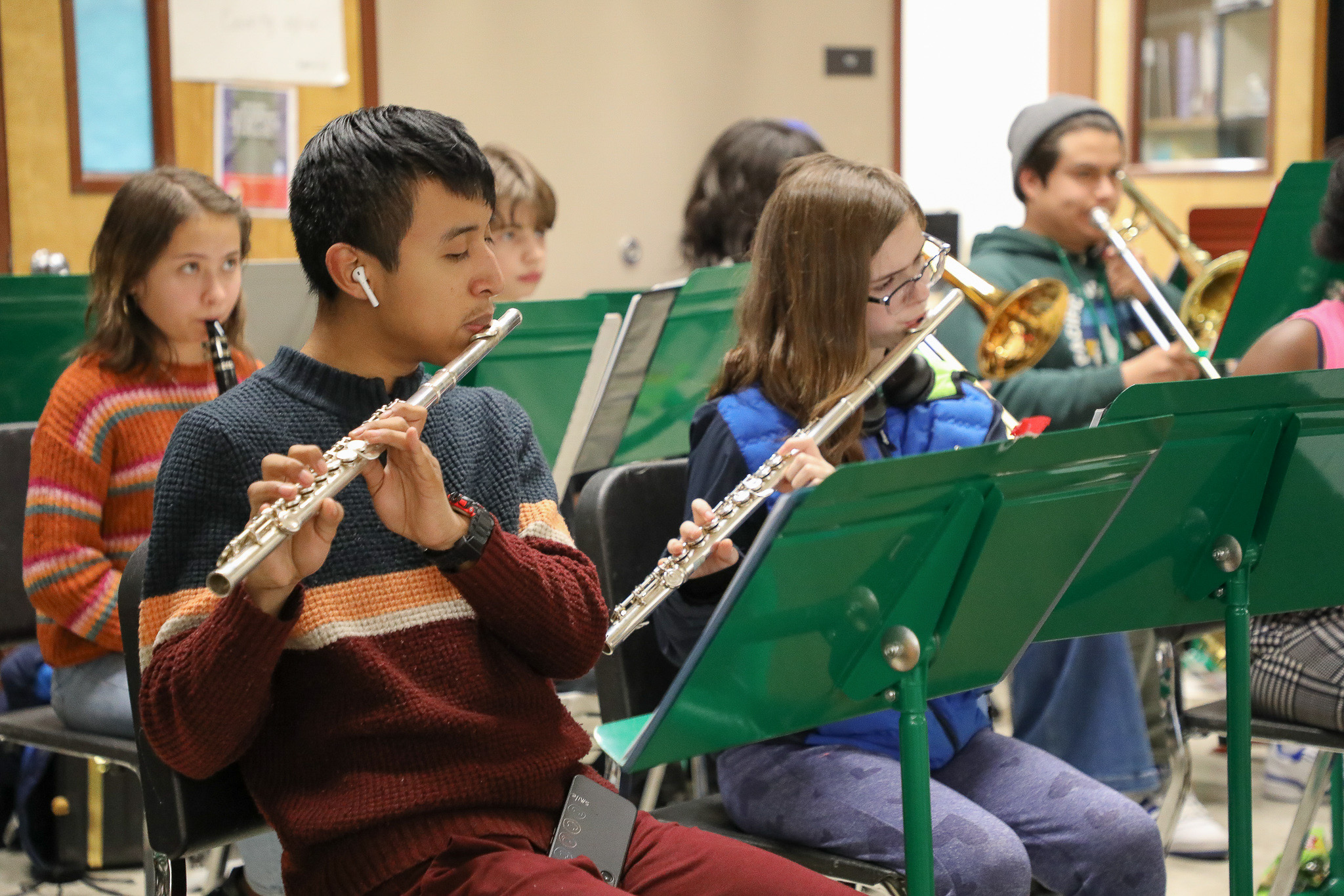 Middle schoolers at Cesar Chavez are seated in front of music stands while playing the flute, clarinet and trumpet.