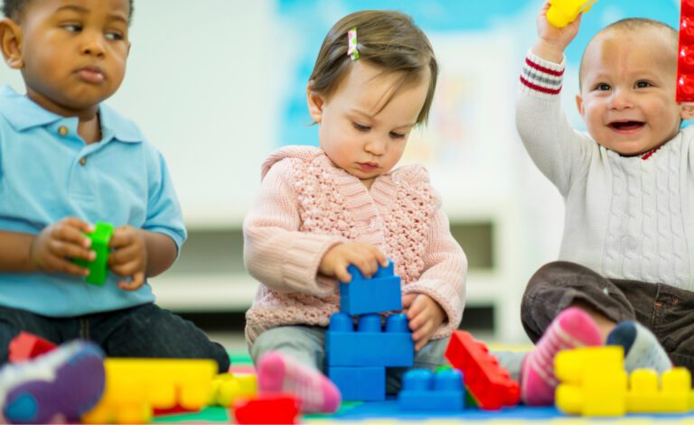 three babies playing with building blocks