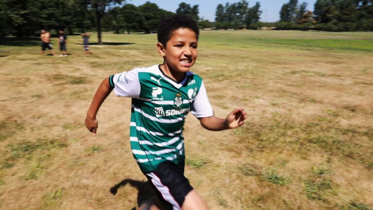 young boy runs across a grassy field during LearnLinks summer camp