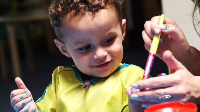 a young child looking at a paint brush