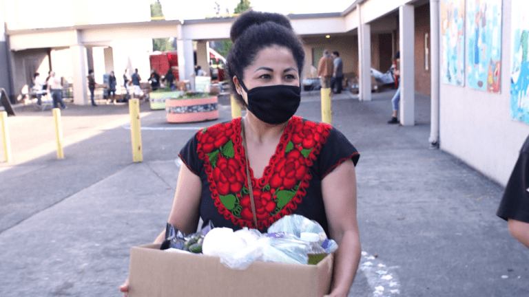 woman wearing a mask holds box of food