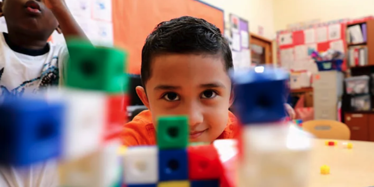 Closeup of a child smiling in focus behind blurred building blocks