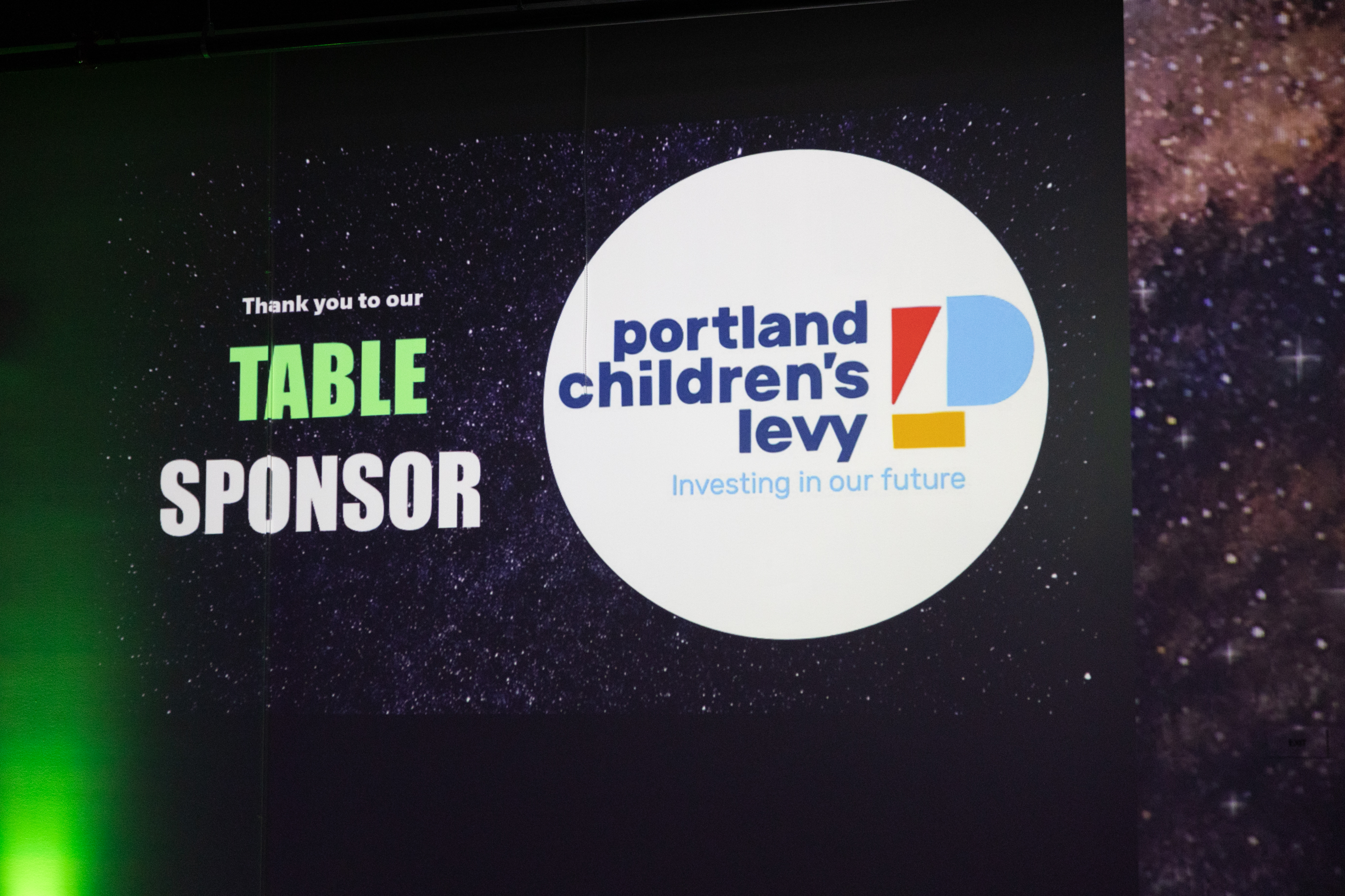 Photo of Portland Children’s Levy logo shown as a table sponsor during a presentation at a Big Brothers Big Sisters event.