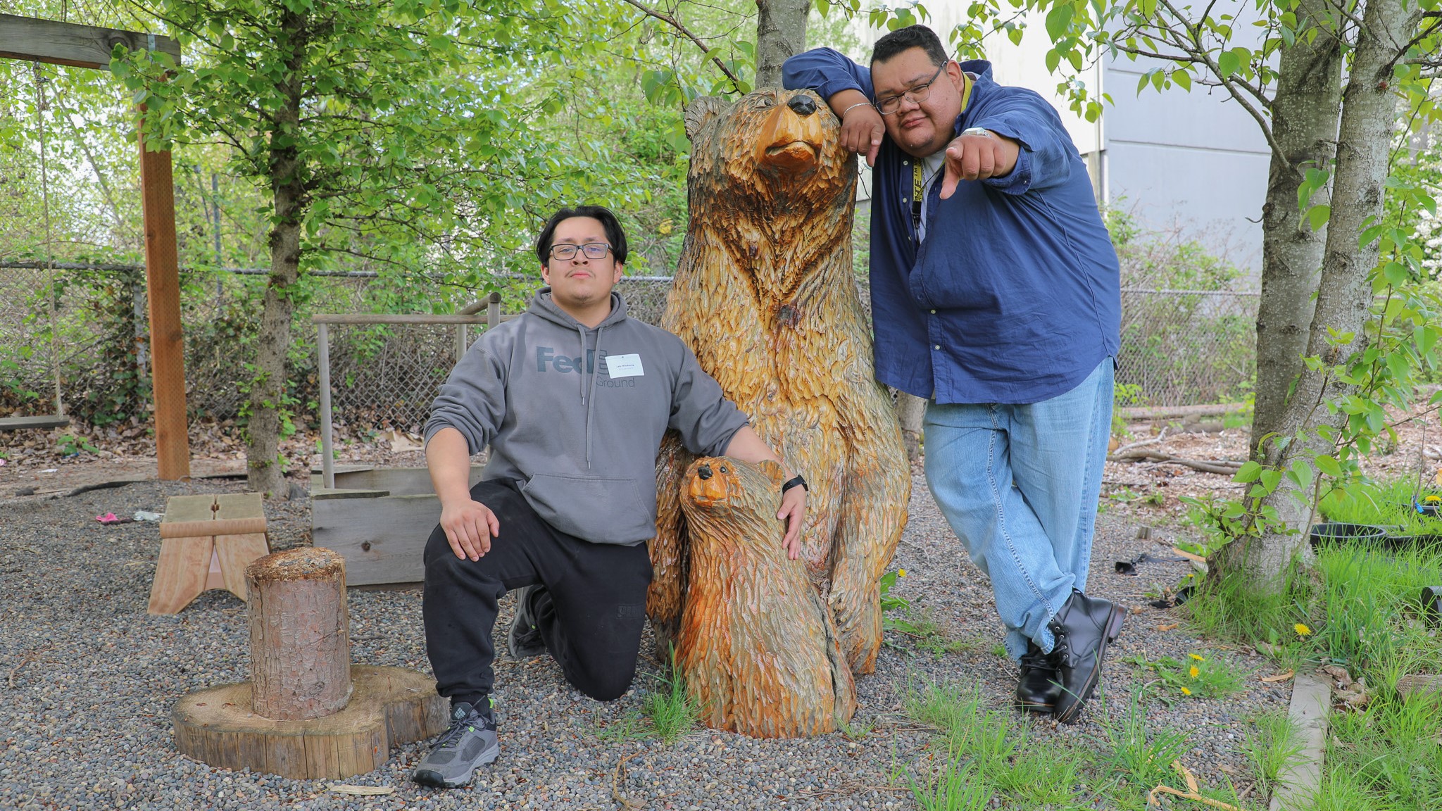photo of NAYA foster care program participant and staffer kneeling and standing next to a carved wooden bear