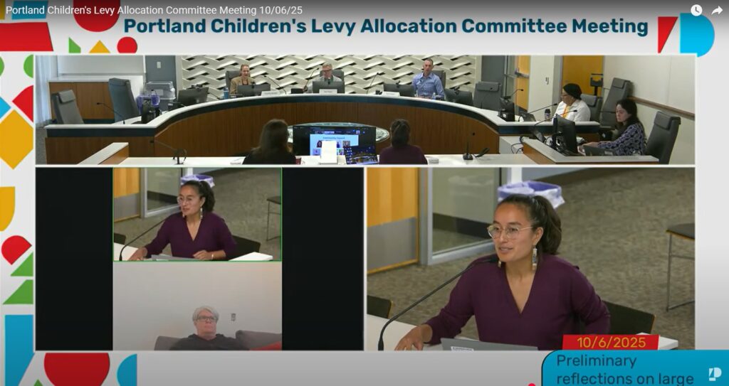 photo from Oct. 6, 2025 Allocation Committee meeting. Katrina Peterson, community engagement coordinator, is seated at a table in front of a microphone speaking.